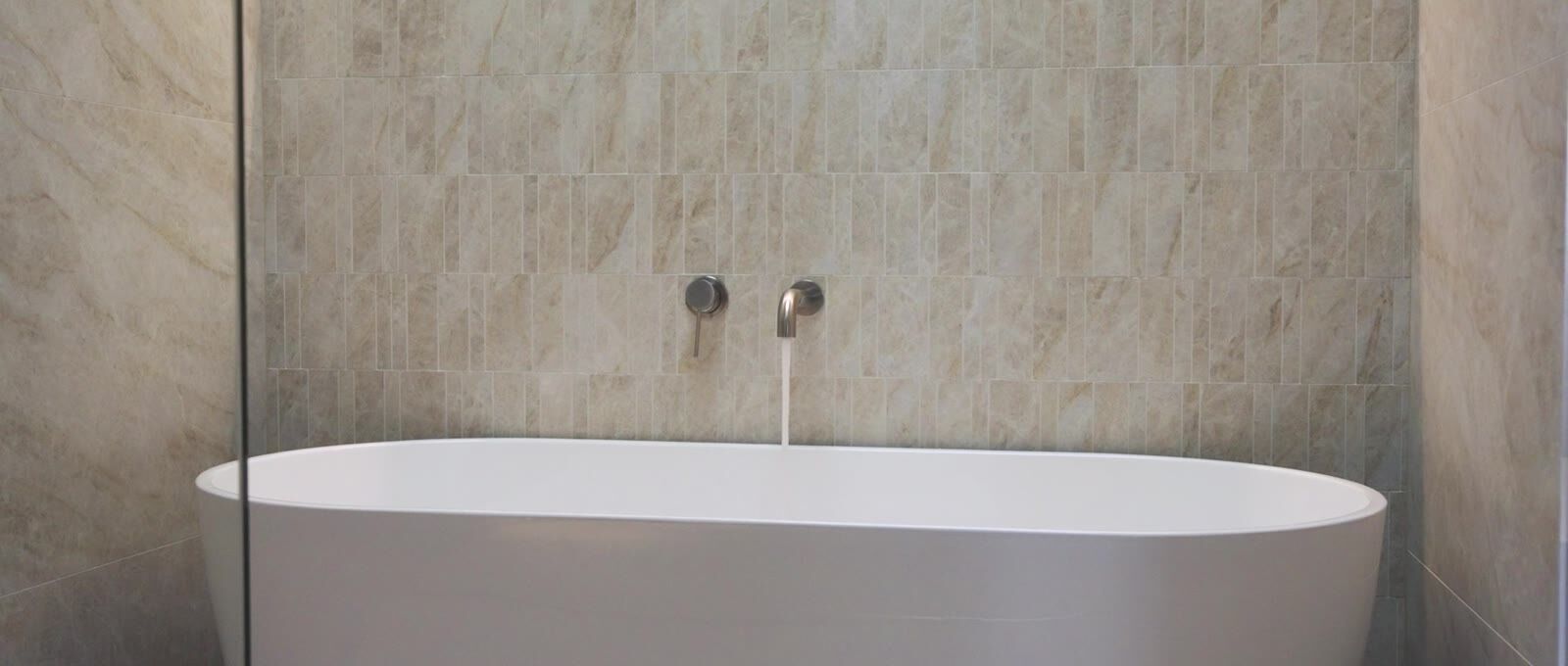 Freestanding bath against floor-to-ceiling travertine tiling