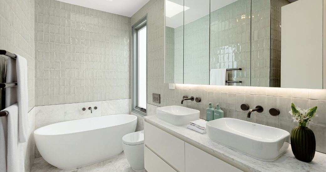 Ensuite bathroom with a freestanding oval bathtub, full-height tiling and a double vanity with wall-mounted tapware.