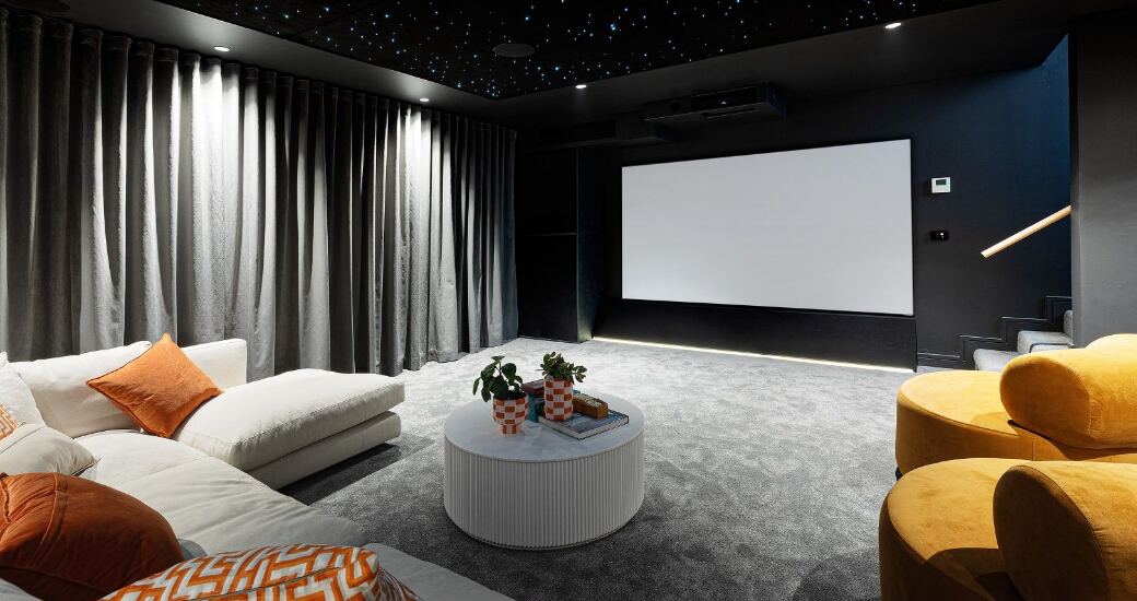 Home theatre with a fibre-optic star ceiling, projector screen and plush sectional seating in cream and mustard tones.