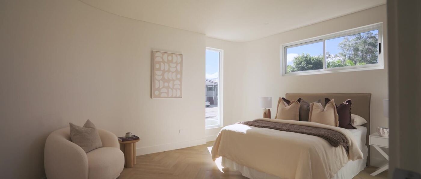 Main bedroom in a soft neutral palette, with upholstered headboard, herringbone oak flooring and full-height windows
