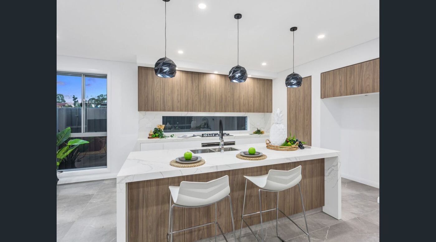 Open-plan kitchen with stone waterfall island benchtop, timber-look cabinetry and pendant lighting