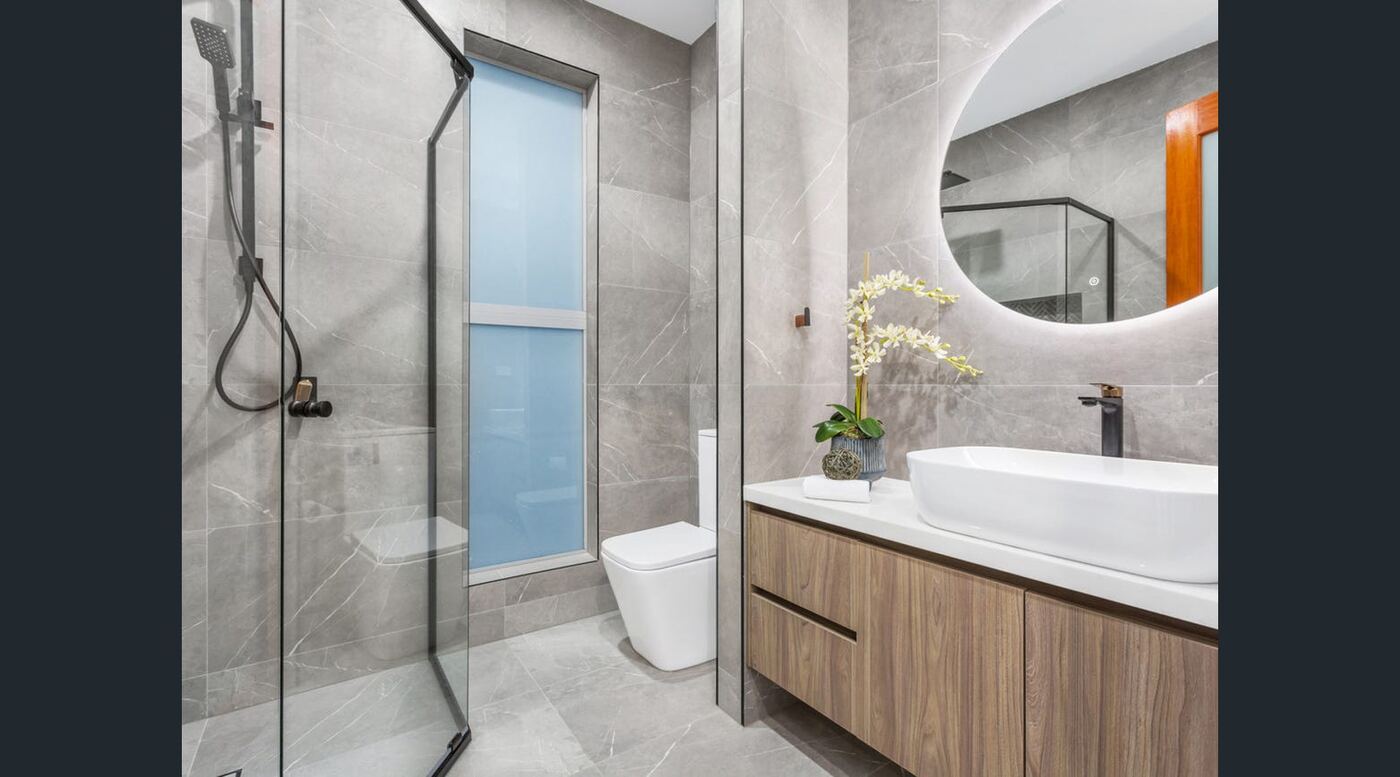 Ensuite with frameless glass shower, backlit round mirror and timber vanity