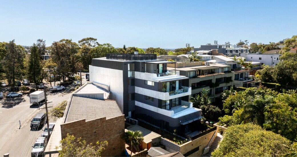 Aerial view of the completed Seaforth building set among neighbouring rooftops and trees, with Middle Harbour visible in the distance.