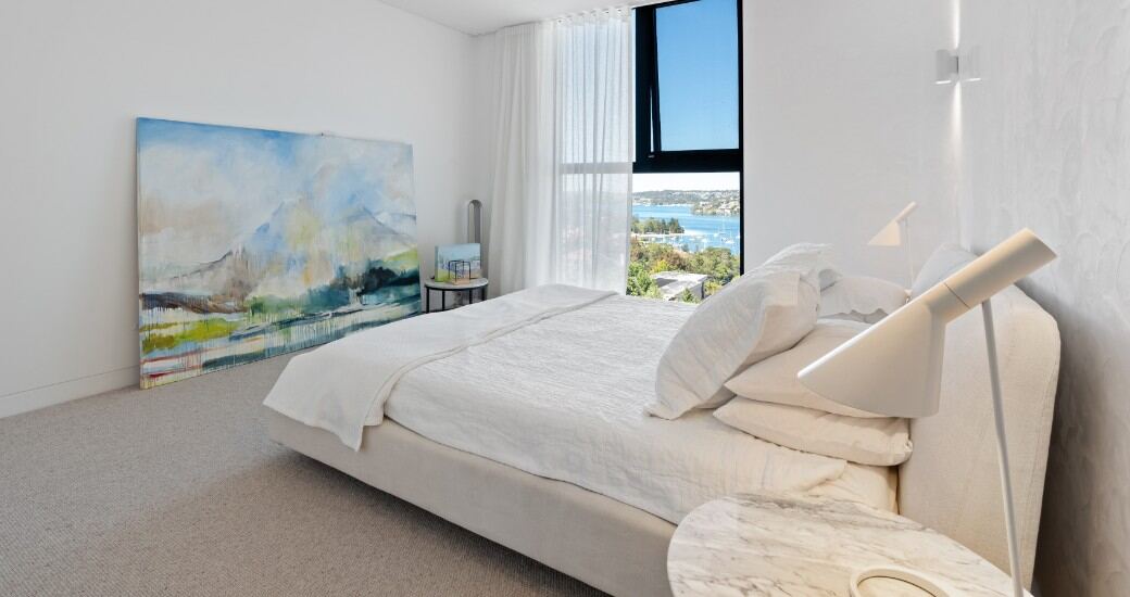 Bedroom with a statement abstract artwork and a floor-to-ceiling window framing water views.